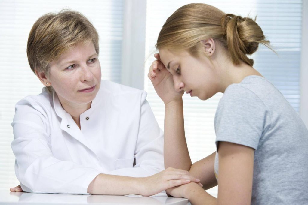 Therapist talk to a juvenile girl with arthritis. Medication is essential in treating arthritis in children until arthritis maintains an inactive status.